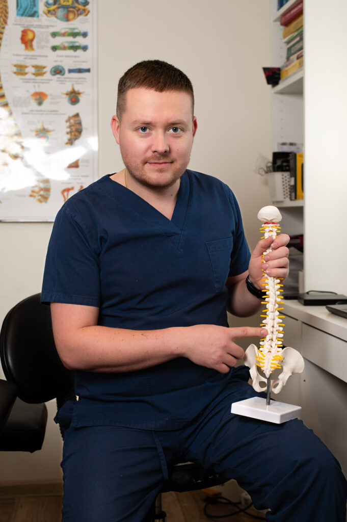 Terapeuta trzyma model kręgosłupa, kadr edukacyjny.